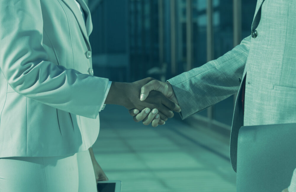 Two business professionals shaking hands, symbolizing trust and verified partnerships through Know Your Business (KYB) checks.