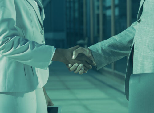 Two business professionals shaking hands, symbolizing trust and verified partnerships through Know Your Business (KYB) checks.