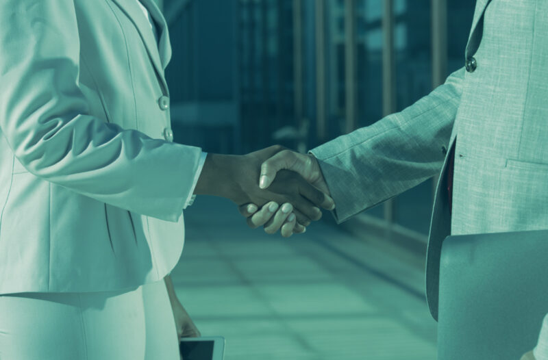 Two business professionals shaking hands, symbolizing trust and verified partnerships through Know Your Business (KYB) checks.