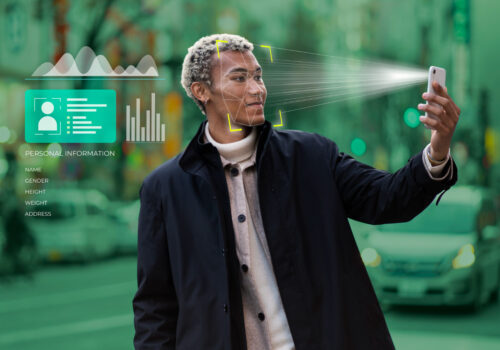 A man holding his face while a biometric scan overlay highlights facial features, with personal information displayed beside him, illustrating background checks in AI matchmaking.
