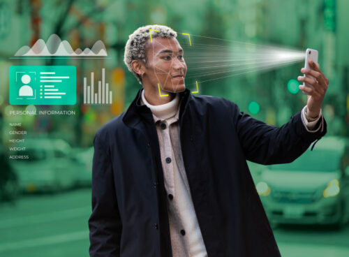 A man holding his face while a biometric scan overlay highlights facial features, with personal information displayed beside him, illustrating background checks in AI matchmaking.