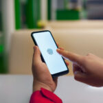 Hand holding smartphone displaying biometric fingerprint scan for secure mobile identity verification.