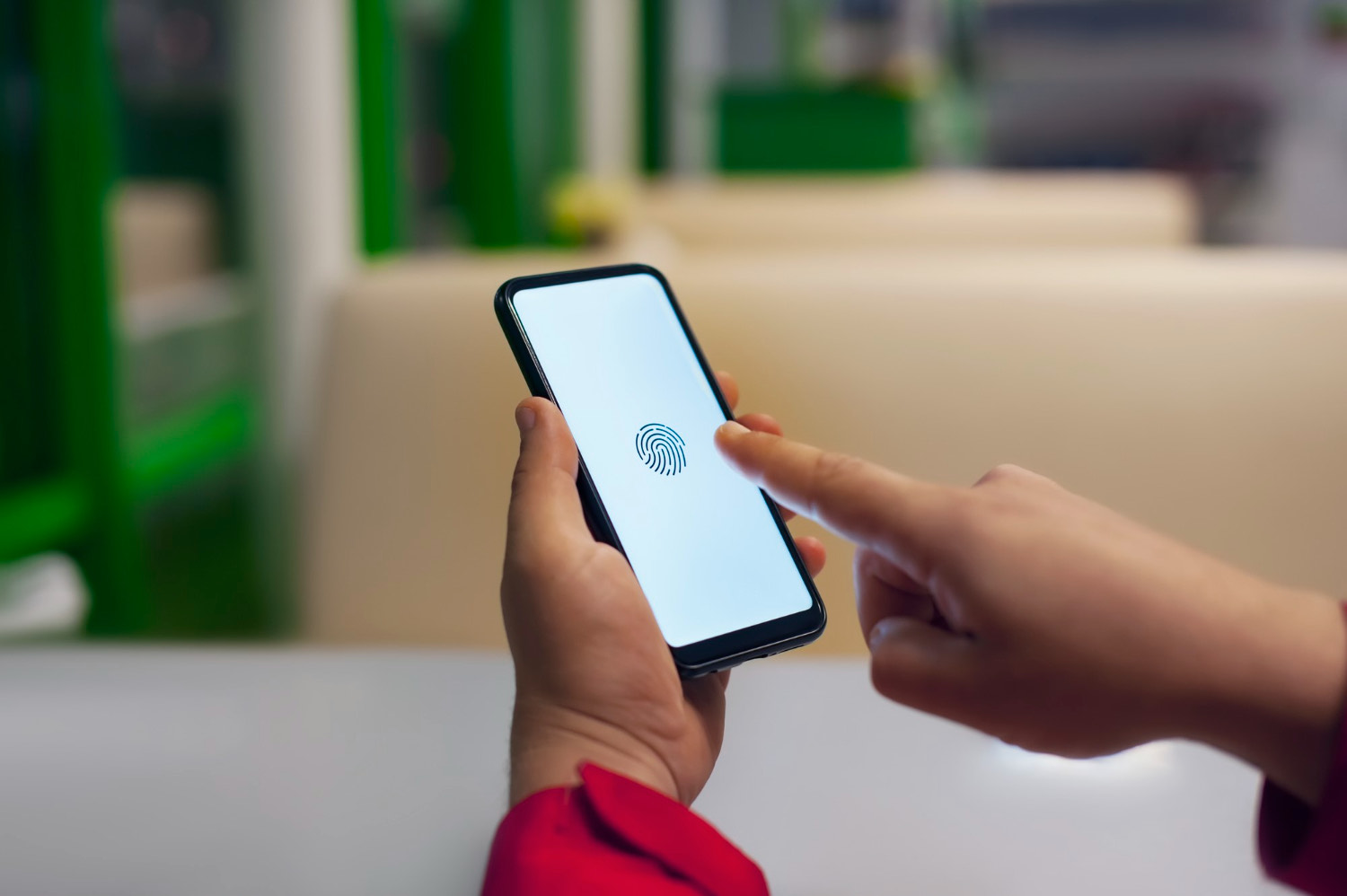 Hand holding smartphone displaying biometric fingerprint scan for secure mobile identity verification.