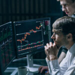 Two professionals reviewing financial data and transaction graphs on a laptop for Anti-Money Laundering (AML) compliance analysis.