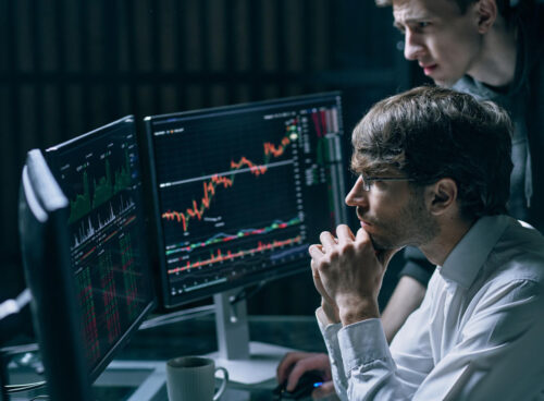 Two professionals reviewing financial data and transaction graphs on a laptop for Anti-Money Laundering (AML) compliance analysis.